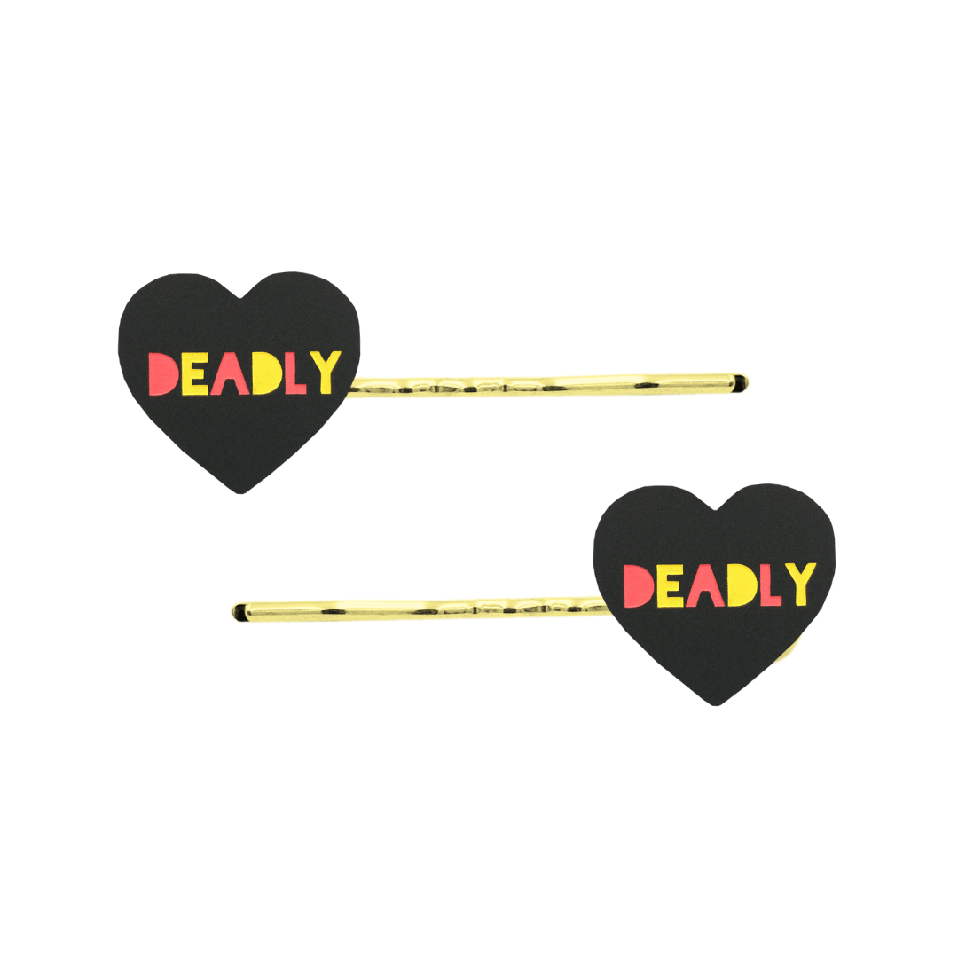 An Image of Haus of Dizzy's Black Acrylic Heart Shaped Hair Pins with "Deadly" text in Red and Yellow. Hearts are on Gold Pins
