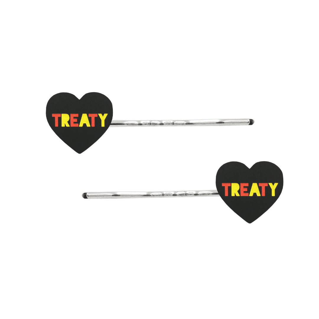 An Image of Haus of Dizzy's Black Acrylic Heart Shaped Hair Pins with "Treaty" text in Red and Yellow. Flags are on Silver Pins