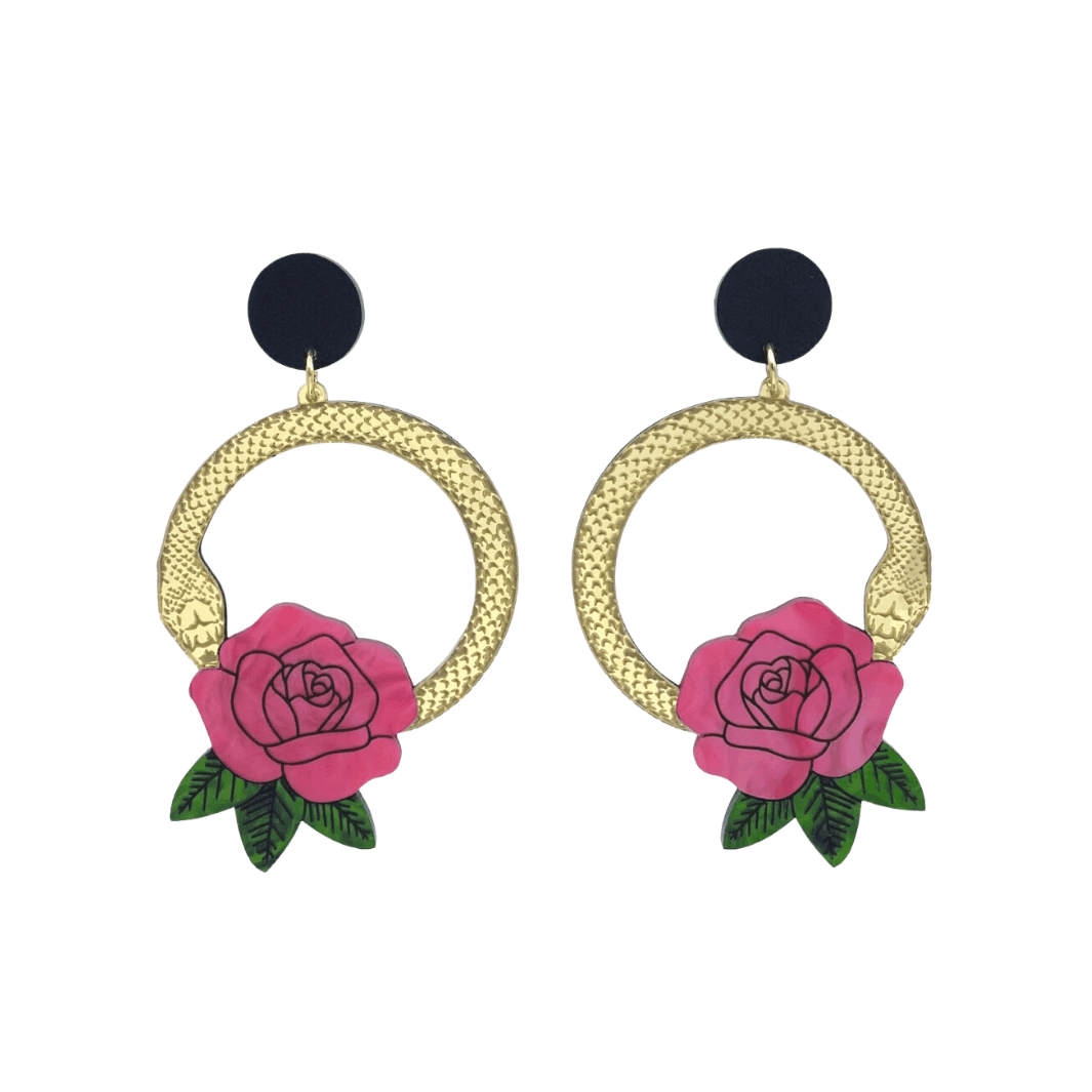 An image of Haus of Dizzy's large Snake Rose hoop dangle earrings, featuring a gold snake in a circle with a light flamingo rose and matte black circle top.