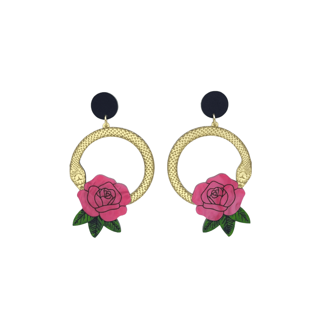 An image of Haus of Dizzy's small Snake Rose hoop dangle earrings, featuring a gold snake in a circle with a light flamingo rose and matte black circle top.