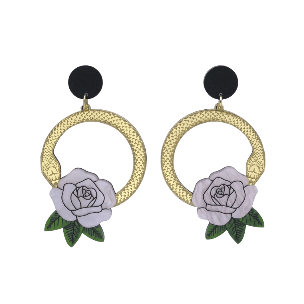 An image of Haus of Dizzy's large Snake Rose hoop dangle earrings, featuring a gold snake in a circle with a light pink rose and matte black circle top.