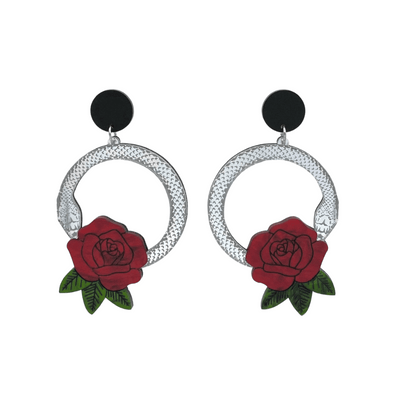 An image of Haus of Dizzy's large Snake Rose hoop dangle earrings, featuring a silver snake in a circle with a blood red rose and matte black circle top.