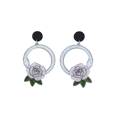 An image of Haus of Dizzy's small Snake Rose hoop dangle earrings, featuring a silver snake in a circle with a light pink rose and matte black circle top.