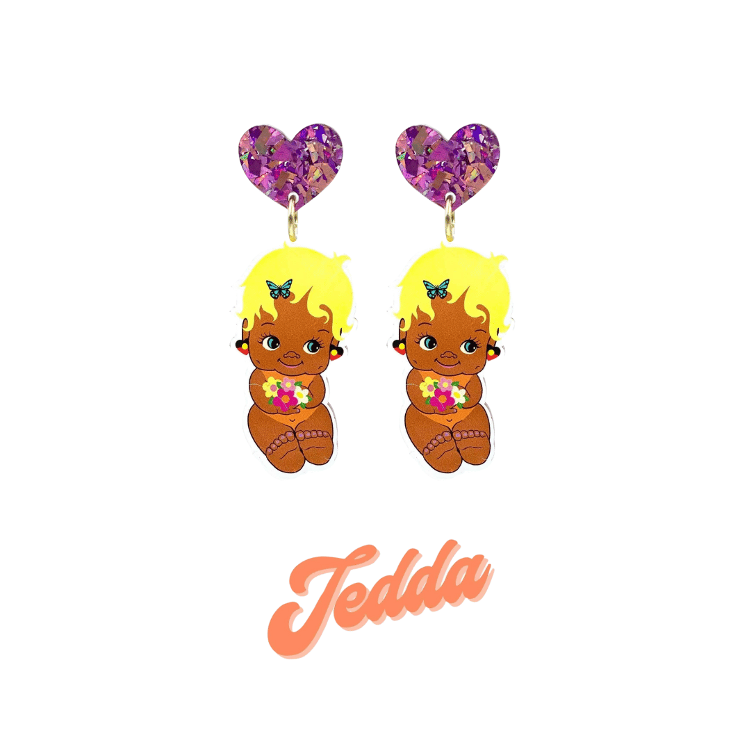 An image of Haus of Dizzy's Dizzy Chicks acrylic dangle earrings, with a doll with pixie length Blonde Wavy hair in a Peach colour Playsuit and Aboriginal Flag earrings on a Purple crinkle glitter heart top. Peach Colour "Jedda" Cursive Text is at the bottom of the image. 