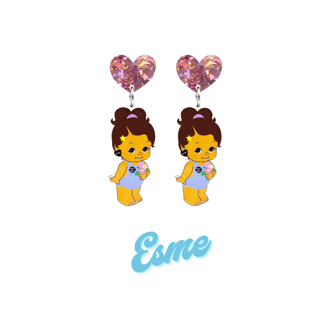 An image of Haus of Dizzy's Dizzy Chicks acrylic dangle earrings, with a doll with Medium length Brown Wavy hair in a ponytail. Wearing a light blue colour Playsuit and Deadly Heart earrings on a Rose Pink crinkle glitter heart top. Esme Colour "Esme" Cursive Text is at the bottom of the image. 