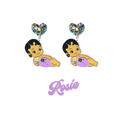 An image of Haus of Dizzy's Dizzy Chicks acrylic dangle earrings, with a doll with short black pixie hair and gold star hair clips in a purple one piece playsuit and Deadly acrylic heart earrings on a purple crinkle glitter heart top. Purple Colour "Rosie" Cursive Text is at the bottom of the image. 