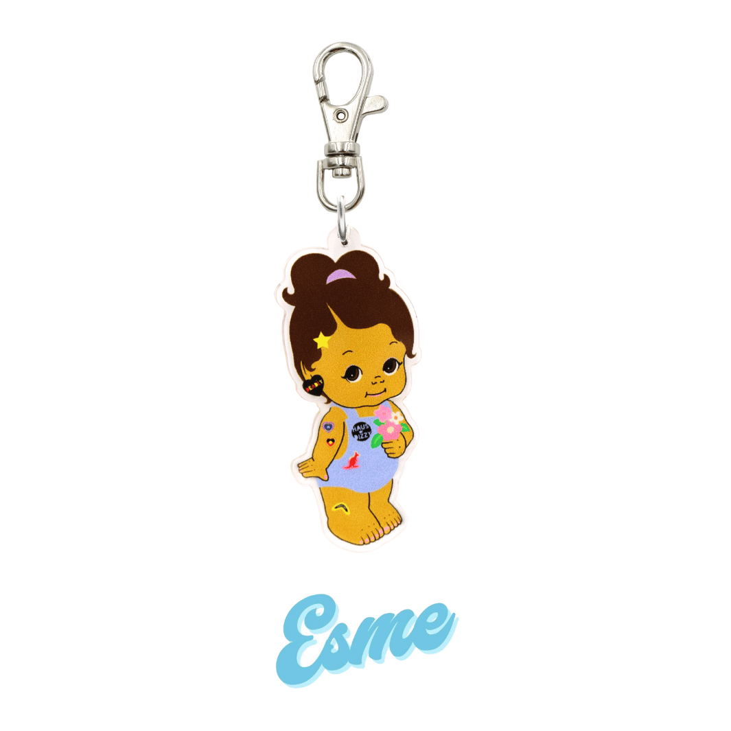 An image of Haus of Dizzy's Dizzy Chicks acrylic keyring, with a doll with Medium length Brown Wavy hair in a ponytail. Wearing a light blue colour Playsuit and Deadly Heart earrings on a parrot clasp. Esme Colour "Esme" Cursive Text is at the bottom of the image.