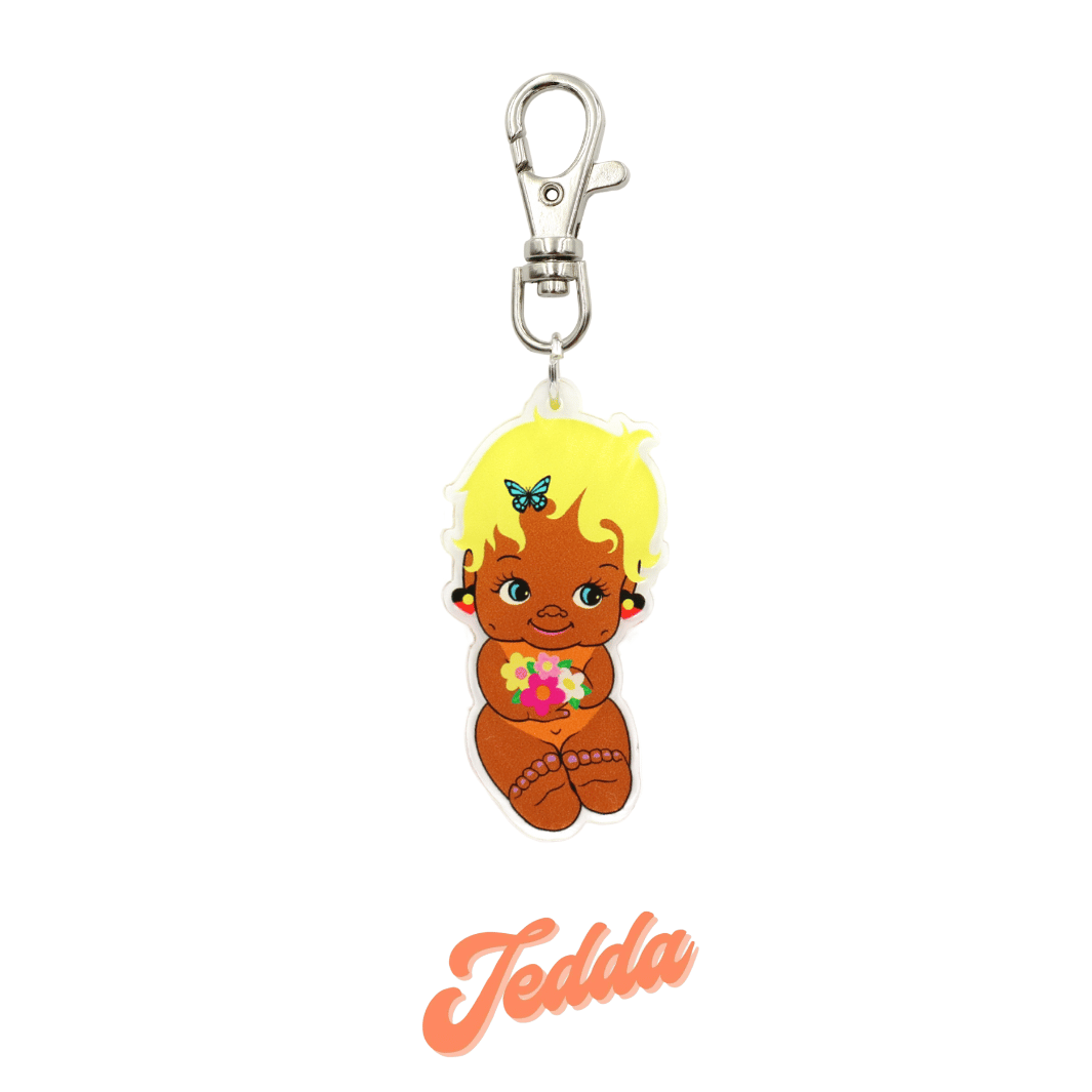 An image of Haus of Dizzy's Dizzy Chicks acrylic keyring, with a doll with pixie length Blonde Wavy hair in a Peach colour Playsuit and Aboriginal Flag earrings on a parrot clasp. Peach Colour "Jedda" Cursive Text is at the bottom of the image. 
