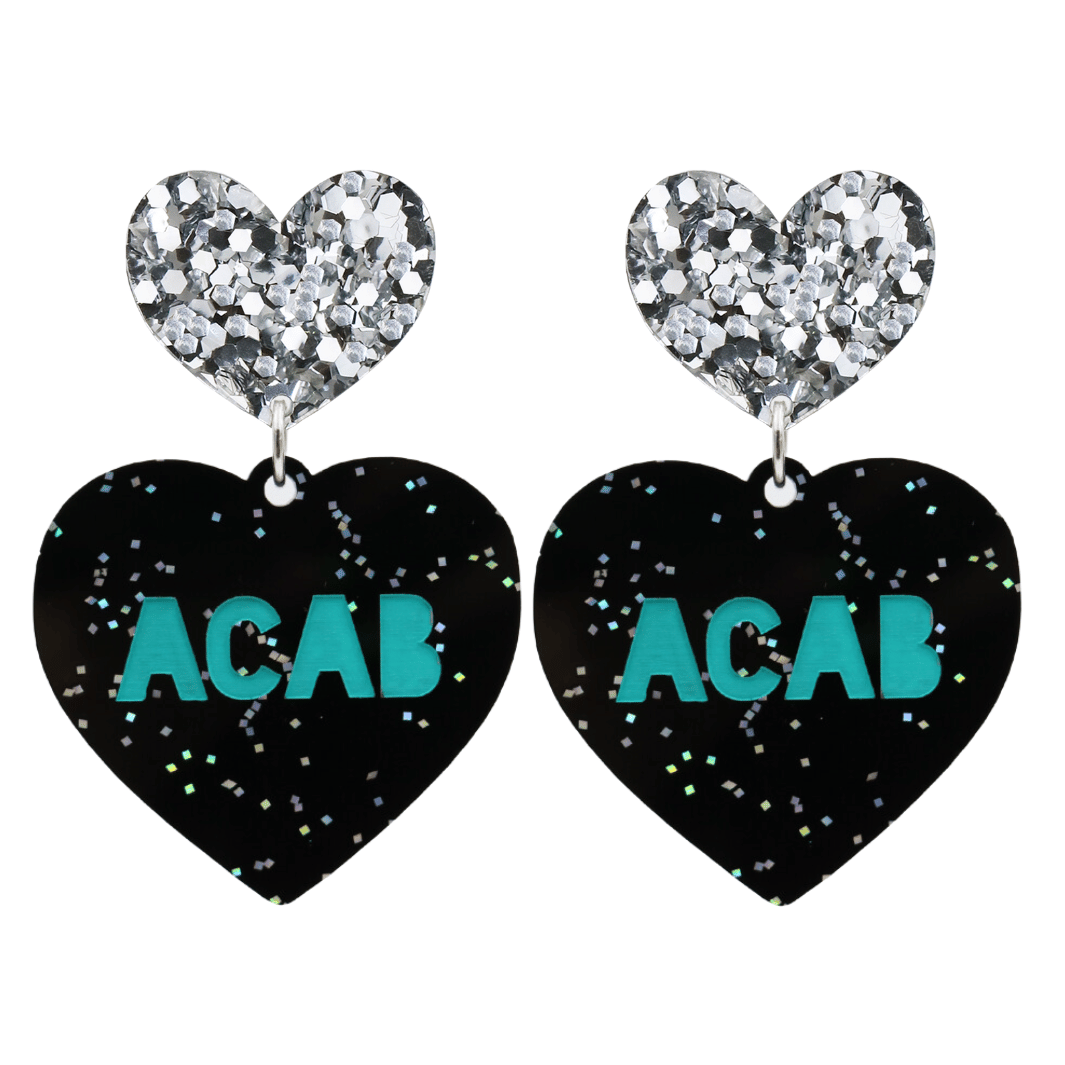 An image of Haus of Dizzy's Large ‘ACAB’ heart shaped dangle earrings, with Emerald Green “ACAB” text on Black Glitter acrylic and a Silver Glitter heart top.