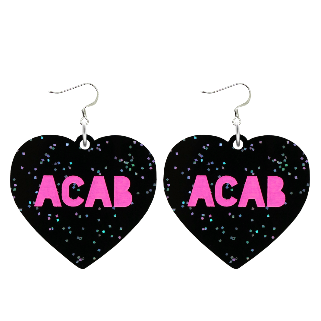 An image of Haus of Dizzy's Large ‘ACAB’ heart shaped dangle earrings, with Hot Pink  “ACAB” text on Black Glitter acrylic and a Hook.