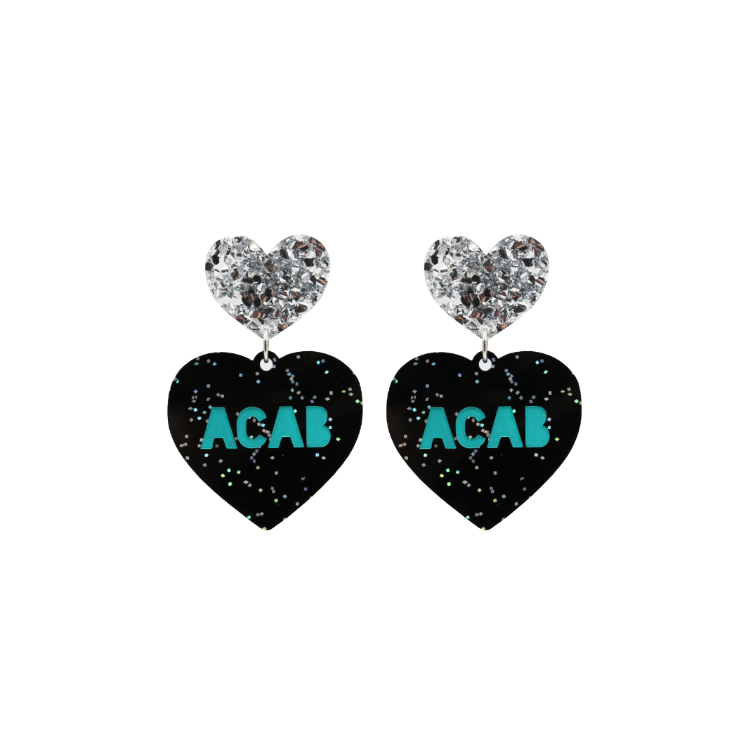 An image of Haus of Dizzy's small ‘ACAB’ heart shaped dangle earrings, with Emerald Green “ACAB” text on Black Glitter acrylic and a Silver Glitter heart top.