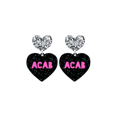 An image of Haus of Dizzy's small ‘ACAB’ heart shaped dangle earrings, with Hot Pink  “ACAB” text on Black Glitter acrylic and a Silver Glitter heart top.