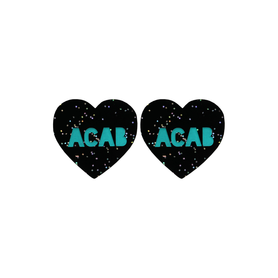 An image of Haus of Dizzy's Small  ‘ACAB’ heart shaped dangle earrings, with Emerald Green “ACAB” text on a Black Glitter acrylic stud heart.