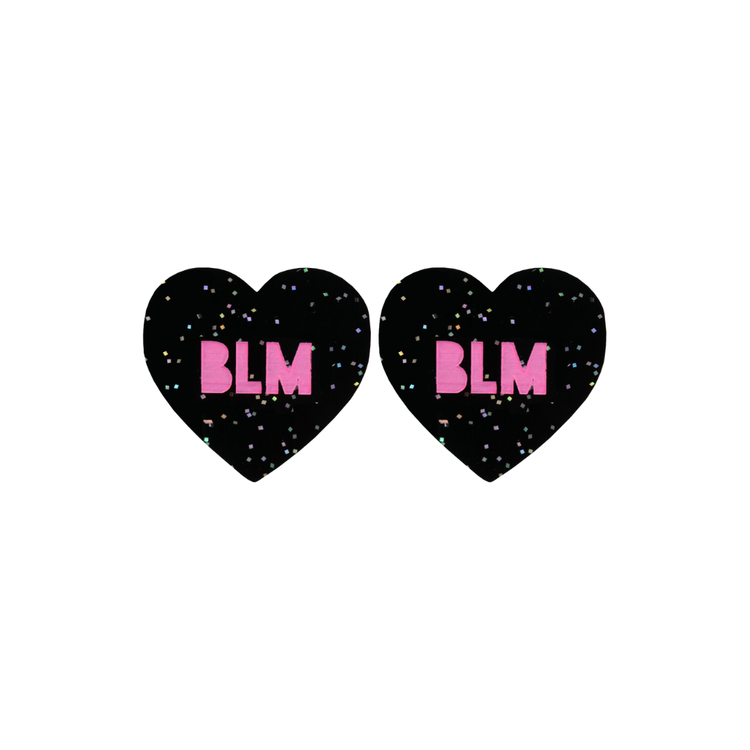 An image of Haus of Dizzy's Small ‘BLM’ heart shaped dangle earrings, with Hot Pink “BLM” text on a Black Glitter acrylic stud heart.