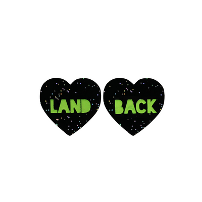 An image of Haus of Dizzy's Small ‘Land Back’ heart shaped dangle earrings, with Apple Green “Land Back” text on a Black Glitter acrylic stud heart.