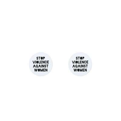 A picture of white acrylic stud earrings that say "stop violence against women" in black text
