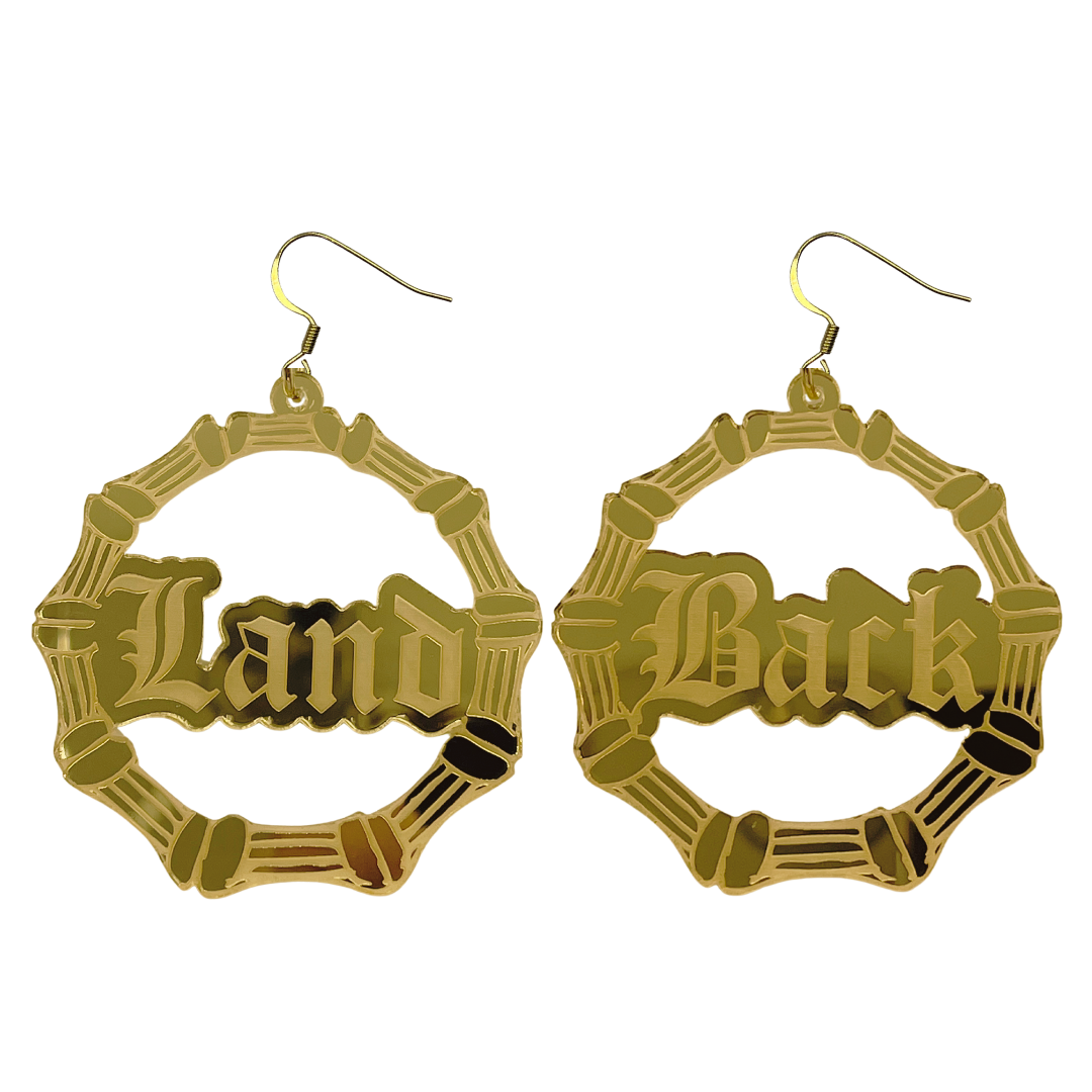 An image of Haus of Dizzy's large dangle bamboo hoop earrings, with Land back text on gold mirror acrylic and hook tops.