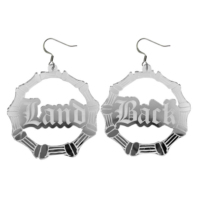 An image of Haus of Dizzy's large dangle bamboo hoop earrings, with Land back text on silver mirror acrylic and hook tops.