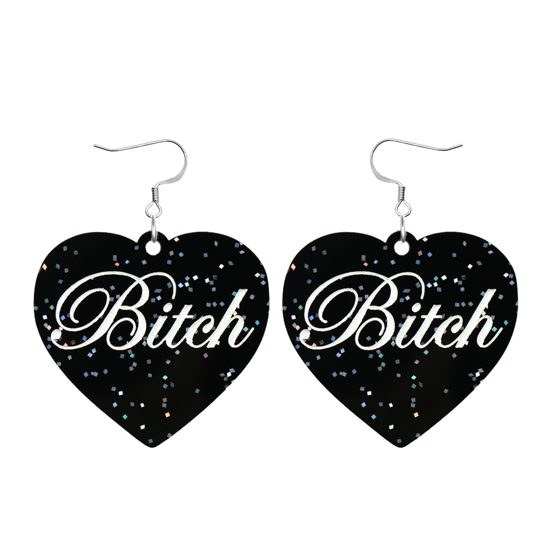 Black glitter Heart-shaped earrings with white text that says 'Bitch', and silver hooks (no heart tops) on a white background
