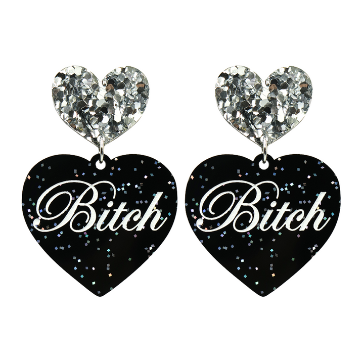 Black glitter Heart-shaped earrings with white text that says 'Bitch', and silver glitter heart tops on a white background