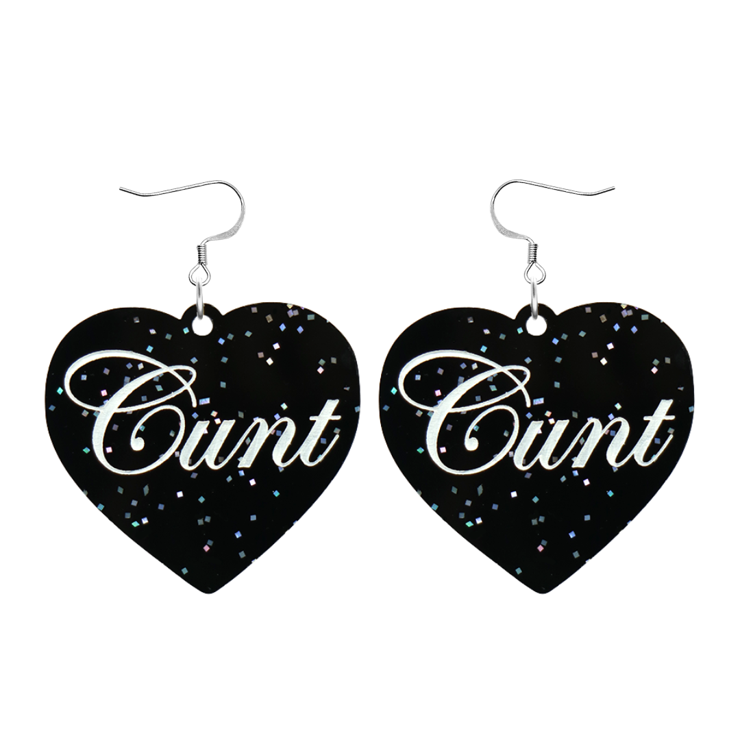 Black glitter Heart-shaped earrings with white text that says 'Cunt', and silver hooks (no heart tops) on a white background