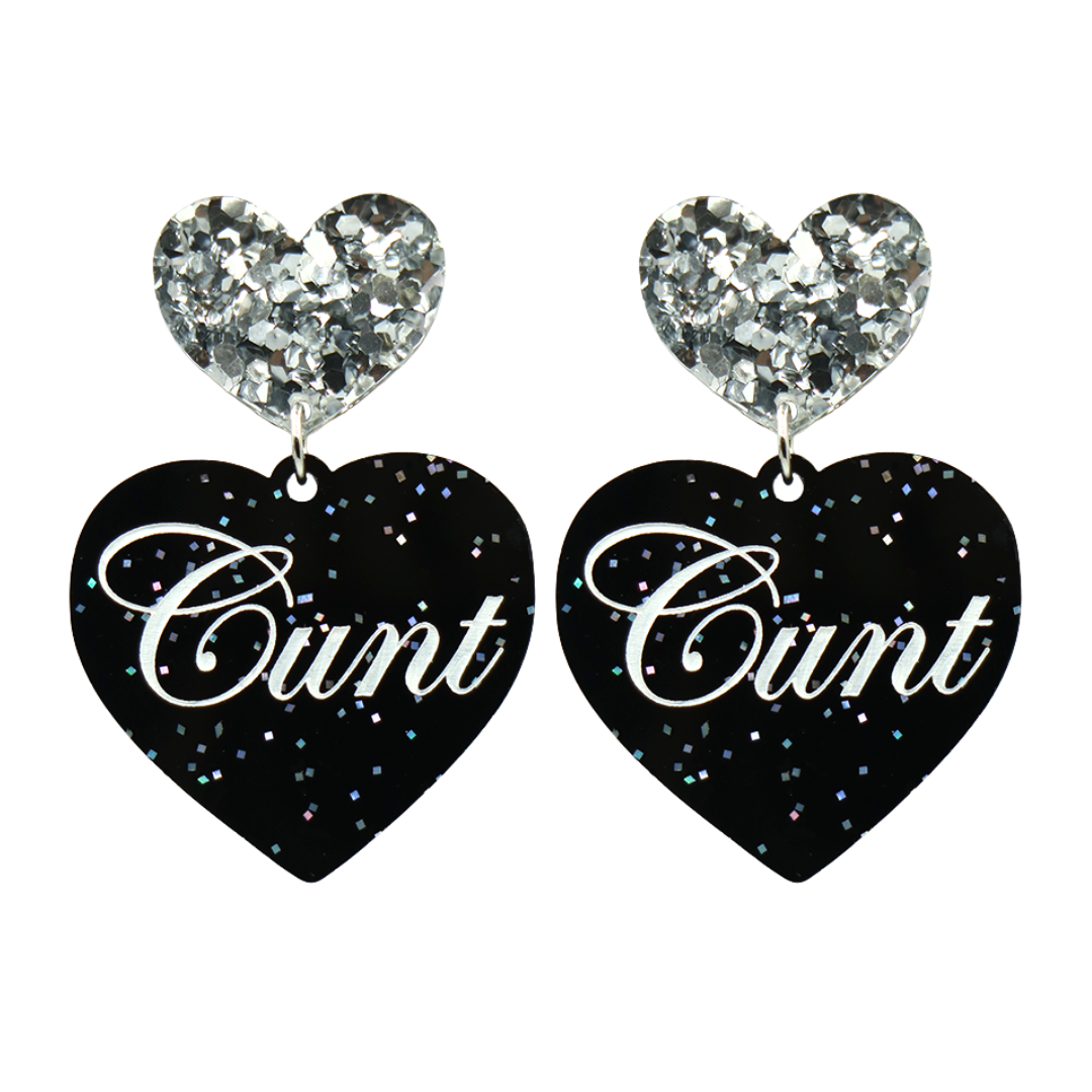 Black glitter Heart-shaped earrings with white text that says 'Cunt', and silver glitter heart tops on a white background