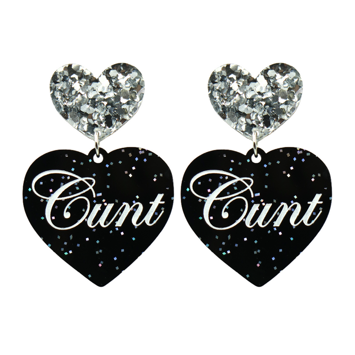 Black glitter Heart-shaped earrings with white text that says 'Cunt', and silver glitter heart tops on a white background