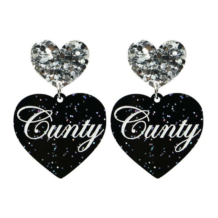 Black glitter Heart-shaped earrings with white text that says 'Cunty', and silver glitter heart tops on a white background