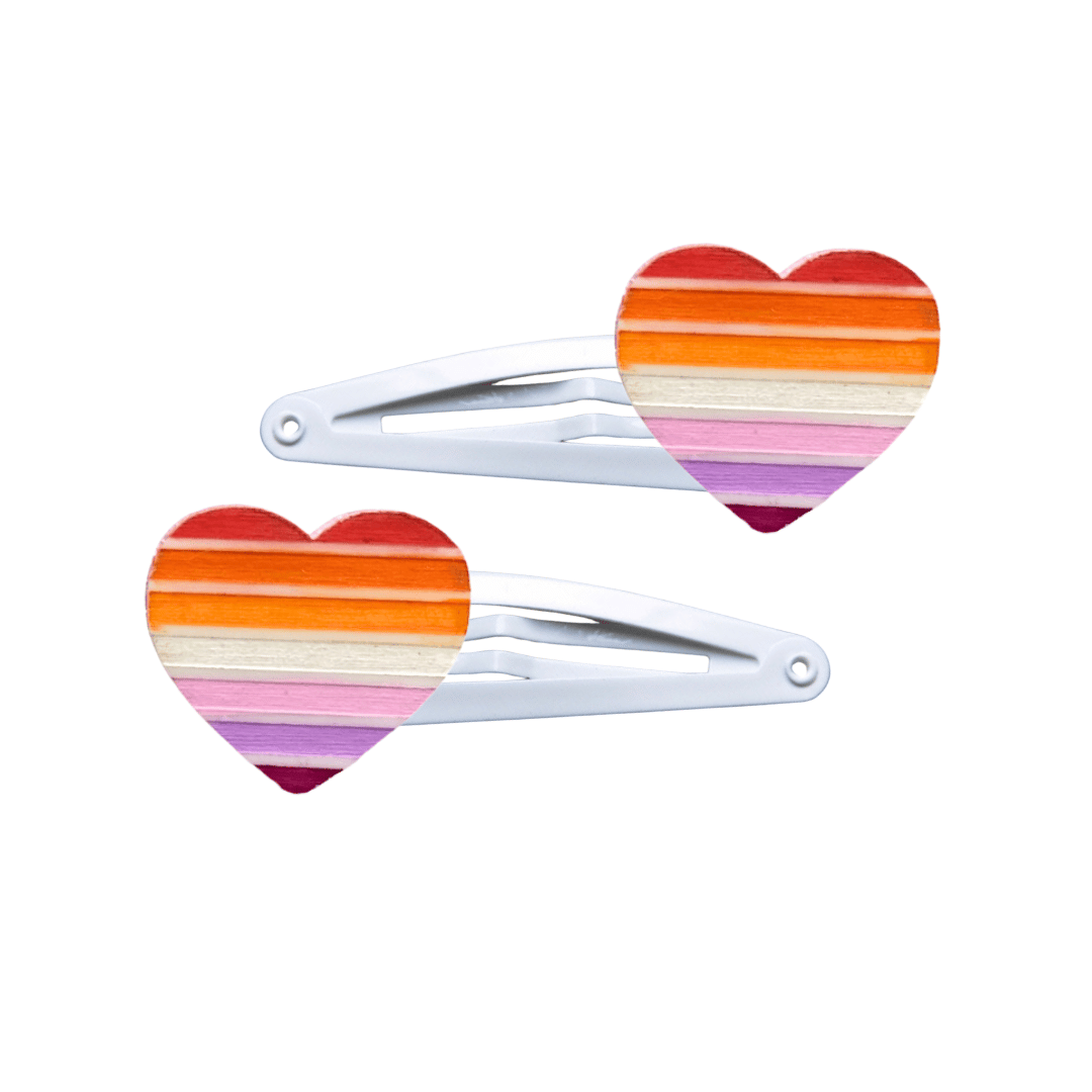 Two heart-shaped lesbian pride flag hair clips on a white background