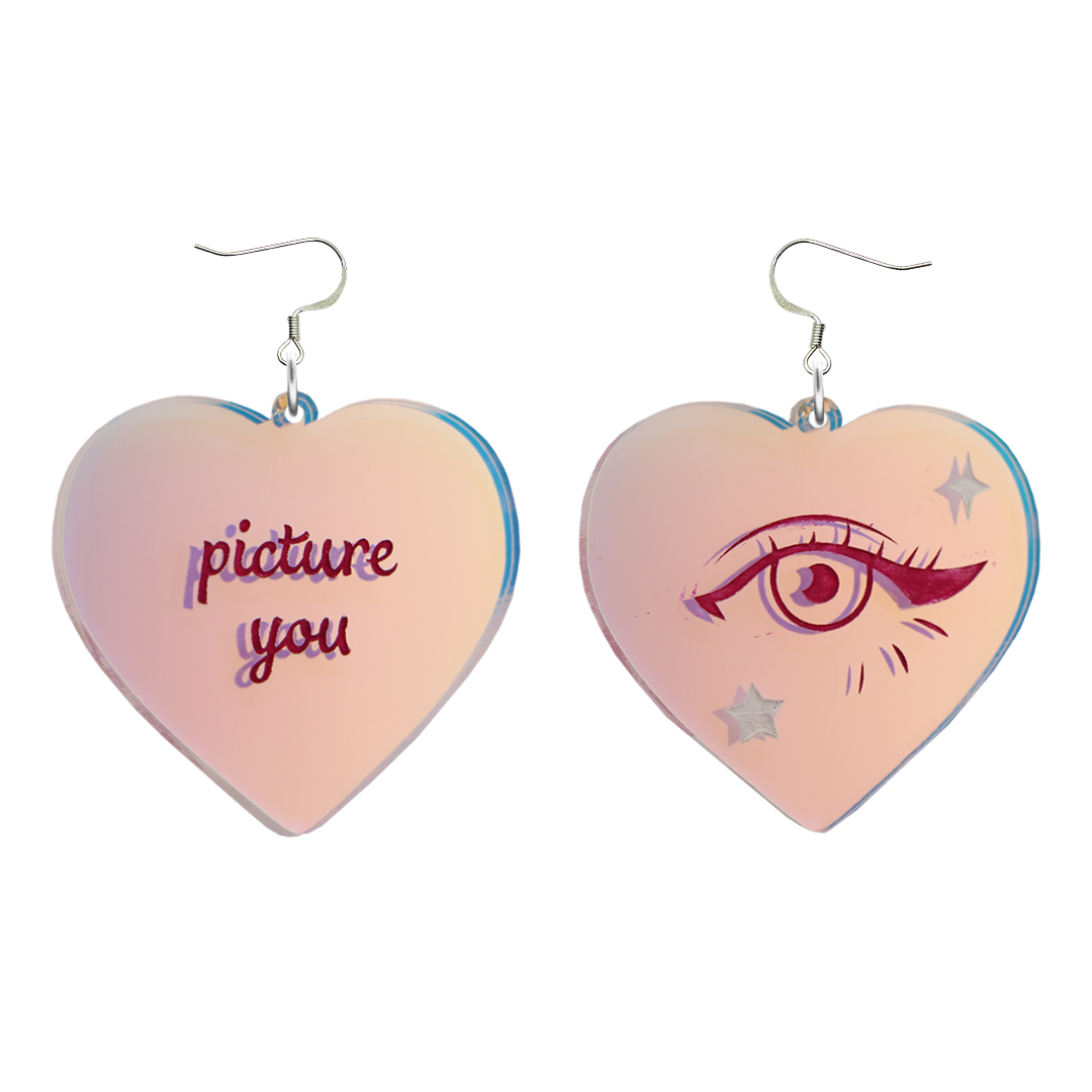 haus of dizzy heart-shaped iridescent earrings with 'picture you' text on one and eye design on the other. on silver hooks. they are on a white background. size large