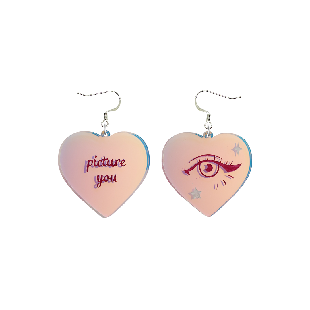 haus of dizzy heart-shaped iridescent earrings with 'picture you' text on one and eye design on the other. on silver hooks. they are on a white background. size large