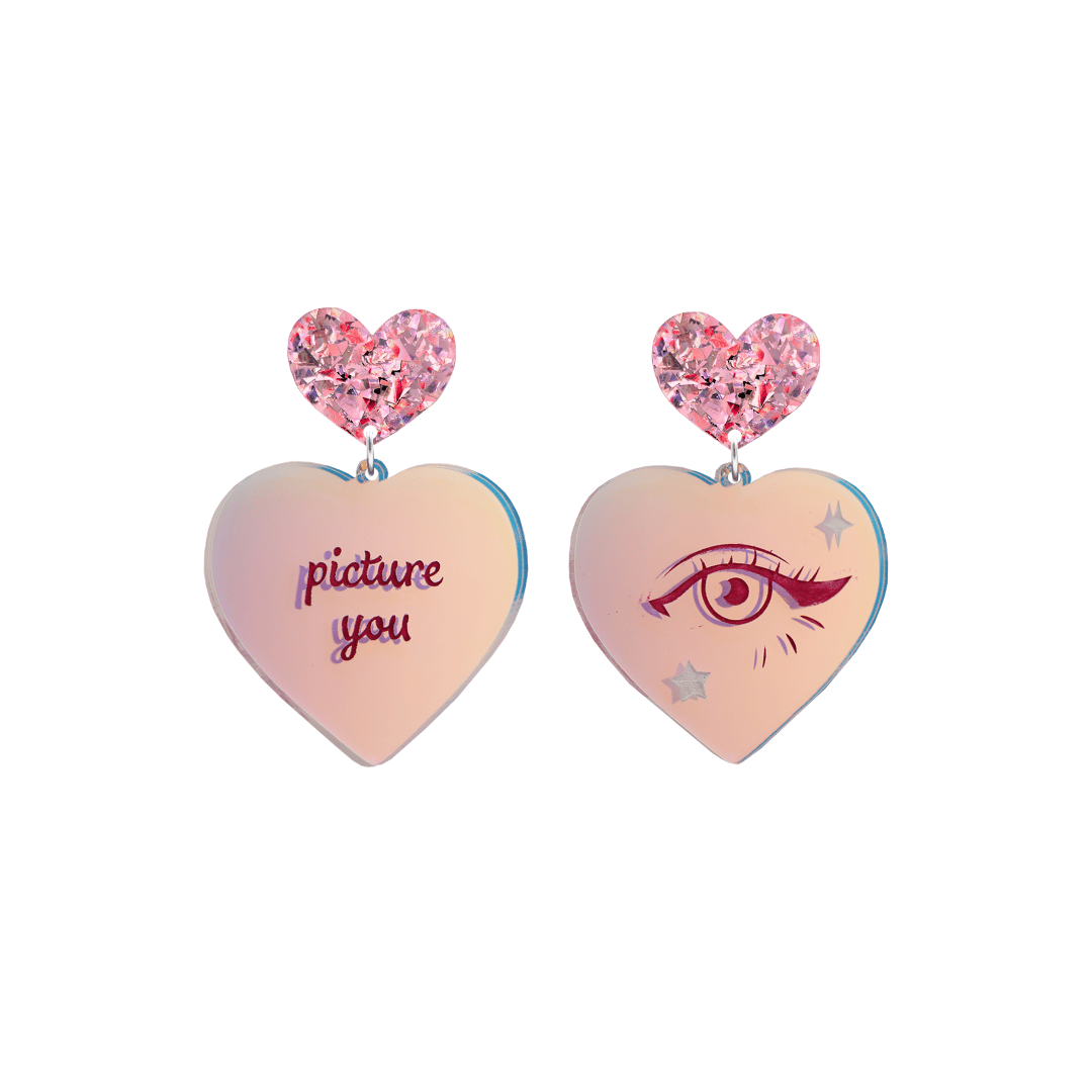 haus of dizzy heart-shaped iridescent earrings with 'picture you' text on one and eye design on the other. pink red chunky glitter heart tops. they are on a white background. size small