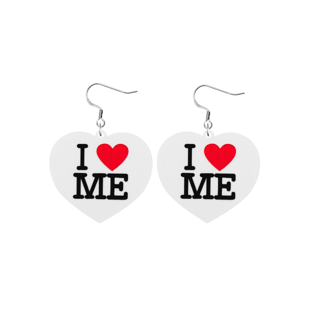 An image of Haus of Dizzy's small I Love Me heart shaped dangle earrings, with I Heart Me text on white acrylic and a hook top.