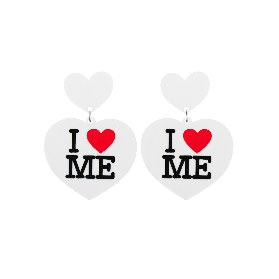 An image of Haus of Dizzy's small I Love Me heart shaped dangle earrings, with I Heart Me text on white acrylic and a white heart top.