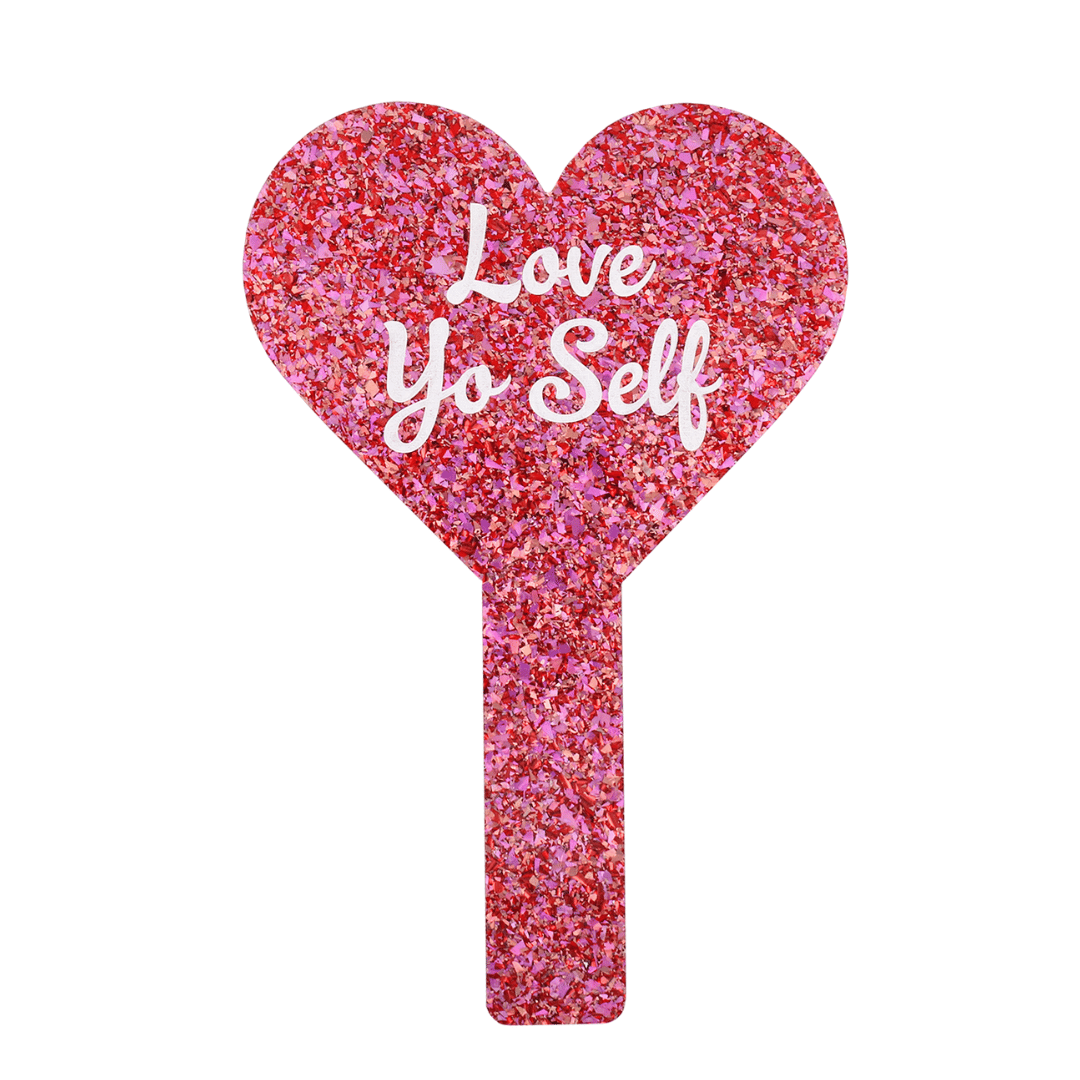 Pink glittery heart-shaped mirror with 'Love Yo Self' text on a white background. image of the back of the mirror.