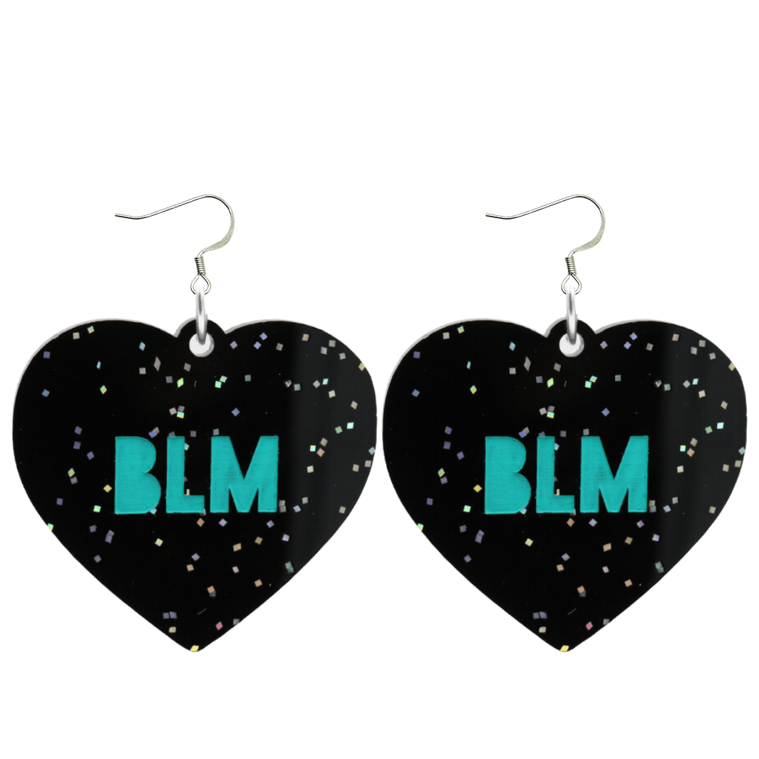 An image of Haus of Dizzy's Large ‘BLM’ heart shaped dangle earrings, with Emerald Green  “BLM’ text on Black Glitter acrylic on Hooks.