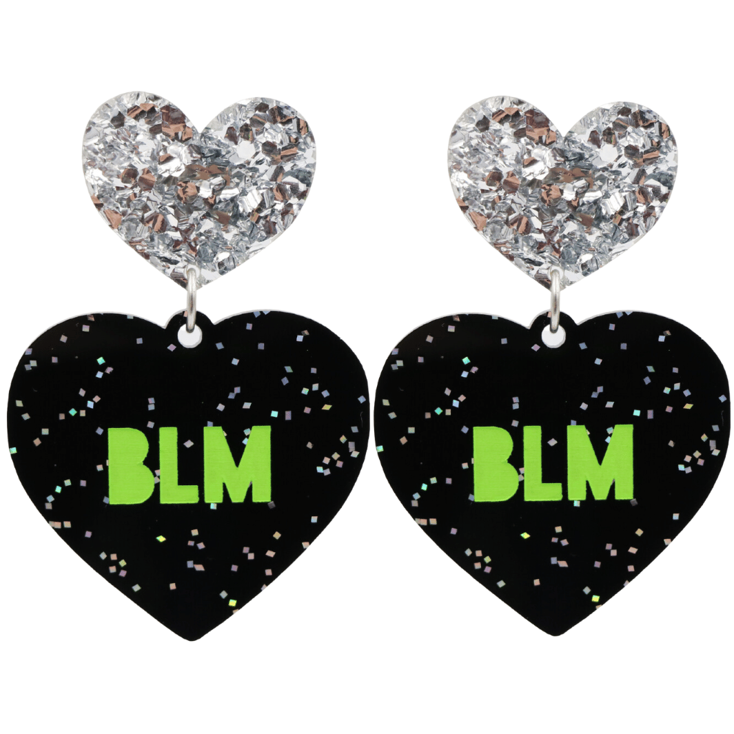 An image of Haus of Dizzy's Large ‘BLM’ heart shaped dangle earrings, with Apple Green  “BLM’ text on Black Glitter acrylic and a Silver Glitter heart top.
