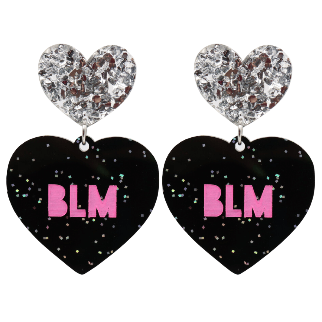 An image of Haus of Dizzy's Large ‘BLM’ heart shaped dangle earrings, with Hot Pink  “BLM’ text on Black Glitter acrylic and a Silver Glitter heart top.