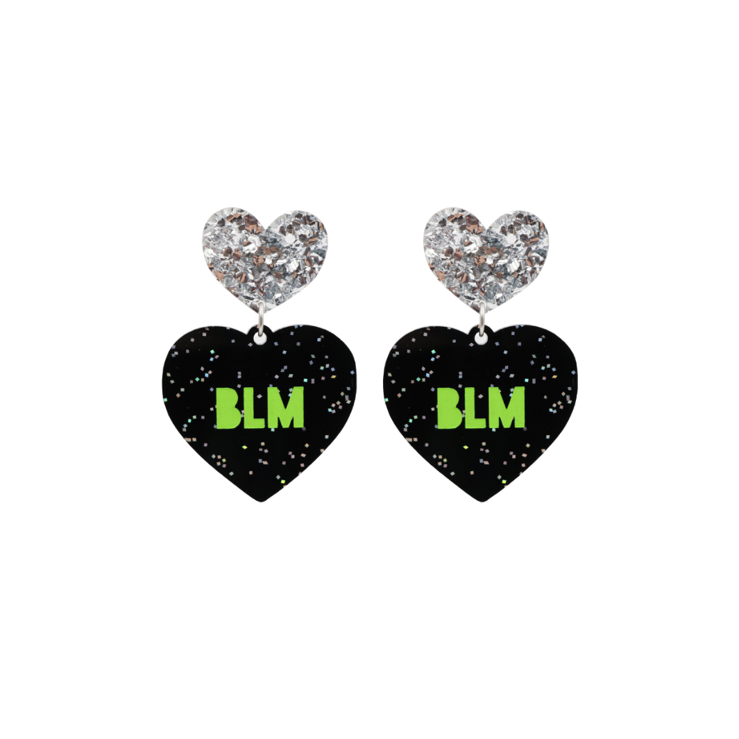 An image of Haus of Dizzy's small ‘BLM’ heart shaped dangle earrings, with Apple Green  “BLM’ text on Black Glitter acrylic and a Silver Glitter heart top.