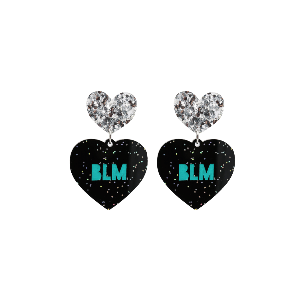 An image of Haus of Dizzy's Small ‘BLM’ heart shaped dangle earrings, with Emerald Green  “BLM’ text on Black Glitter acrylic and a Silver Glitter heart top.