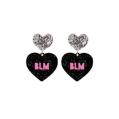  An image of Haus of Dizzy's Large ‘BLM’ heart shaped dangle earrings, with Hot Pink  “BLM’ text on Black Glitter acrylic and a Silver Glitter heart top.