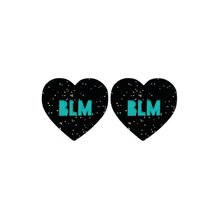 An image of Haus of Dizzy's Small ‘BLM’ heart shaped dangle earrings, with Emerald Green “BLM” text on a Black Glitter acrylic stud heart.