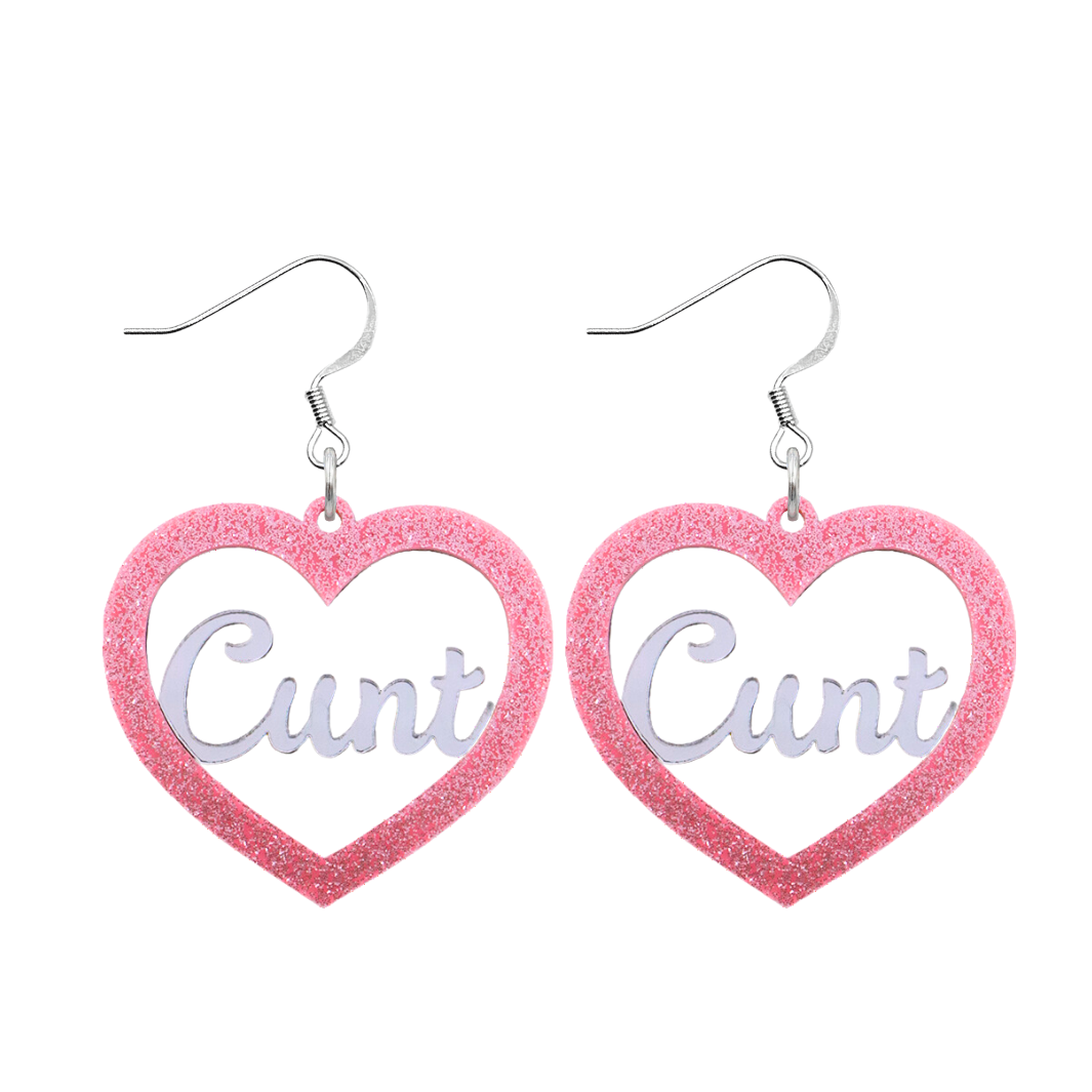 An image of Haus of Dizzy's Small ‘Cunt' heart shaped dangle earrings, with mirror "Cunt" text on a Baby Pink Glitter acrylic on a hook.