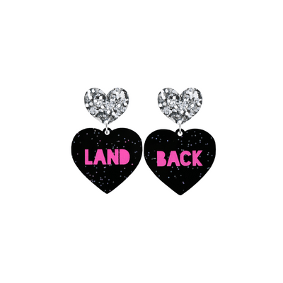  An image of Haus of Dizzy's small Land Back heart shaped dangle earrings, with Hot Pink Land Back text on Black Chunky Glitter acrylic and a Silver Glitter heart top.