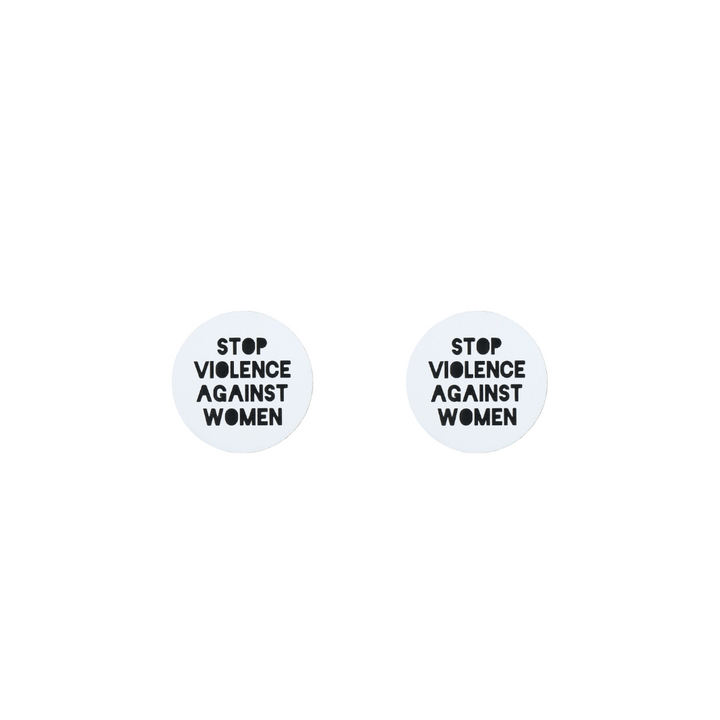 A picture of white acrylic stud earrings that say "stop violence against women" in black text