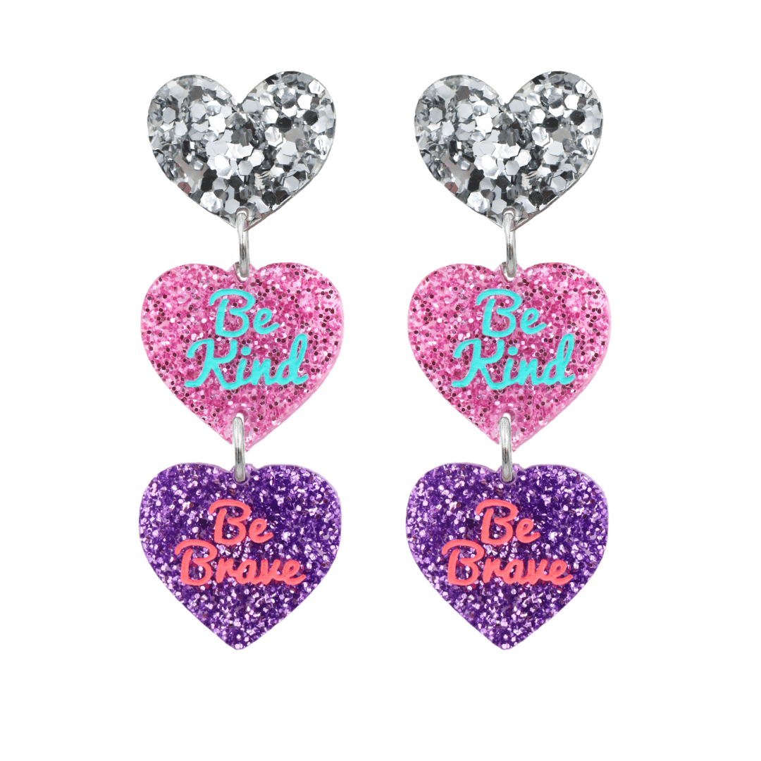 haus of Dizzy Stacked 'Be Brave, Be Kind' earrings with hearts in chunky silver glitter, pink glitter, and purple glitter, with hand painted text on each heart