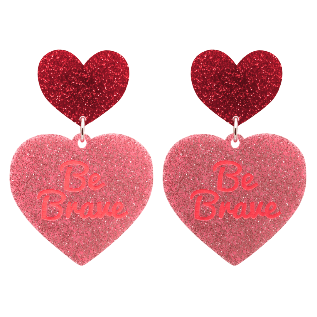 haus of dizzy baby pink glitter heart-shaped acrylic earrings with bright red 'Be Brave' text and red glitter heart tops size large