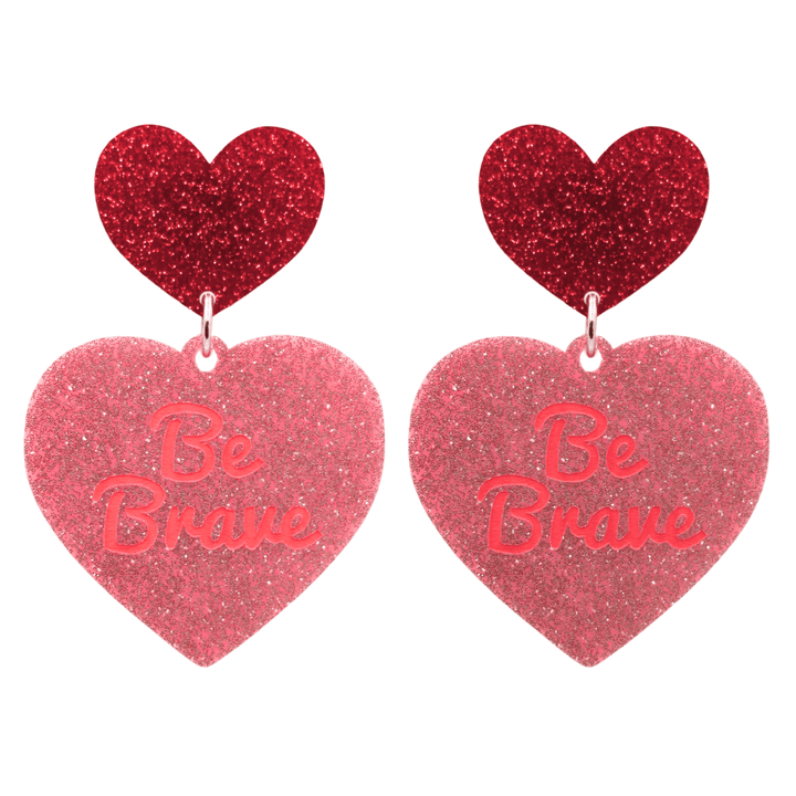 haus of dizzy baby pink glitter heart-shaped acrylic earrings with bright red 'Be Brave' text and red glitter heart tops size large