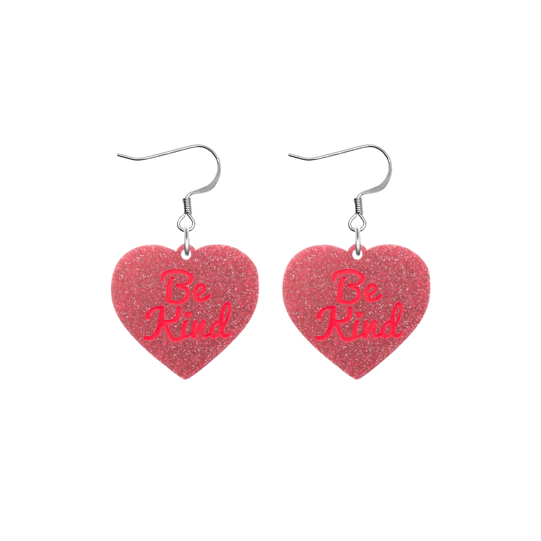 haus of dizzy baby pink glitter heart-shaped acrylic earrings with bright red 'Be Kind' text and silver hooks no heart tops size small