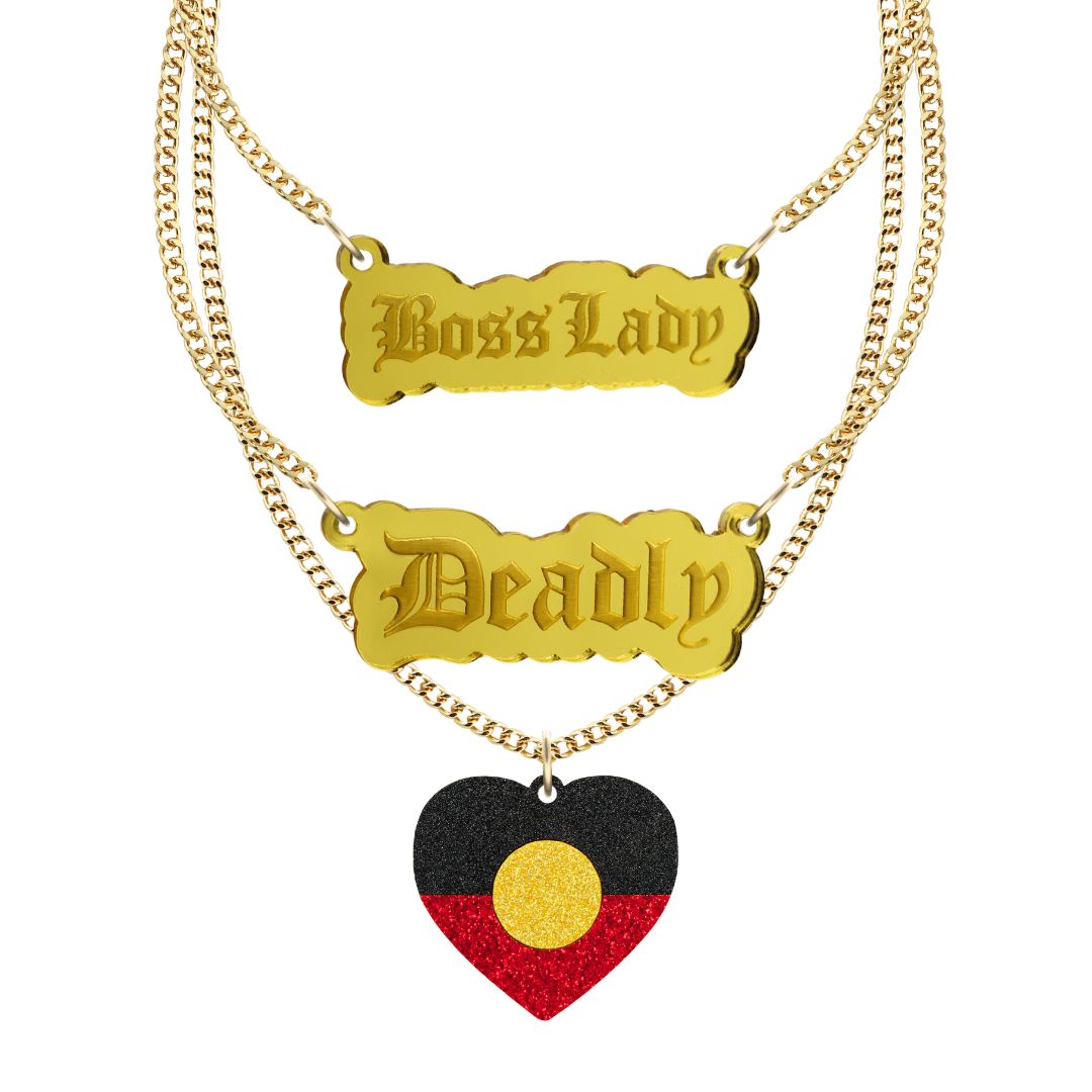 haus of dizzy three tier stacked necklace set with two silver pendants, one says boss lady the other says deadly, the third necklace has an aboriginal flag glitter heart. all on gold chain